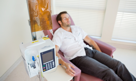 Photo of man sitting in chair with device next to him monitoring vitals.